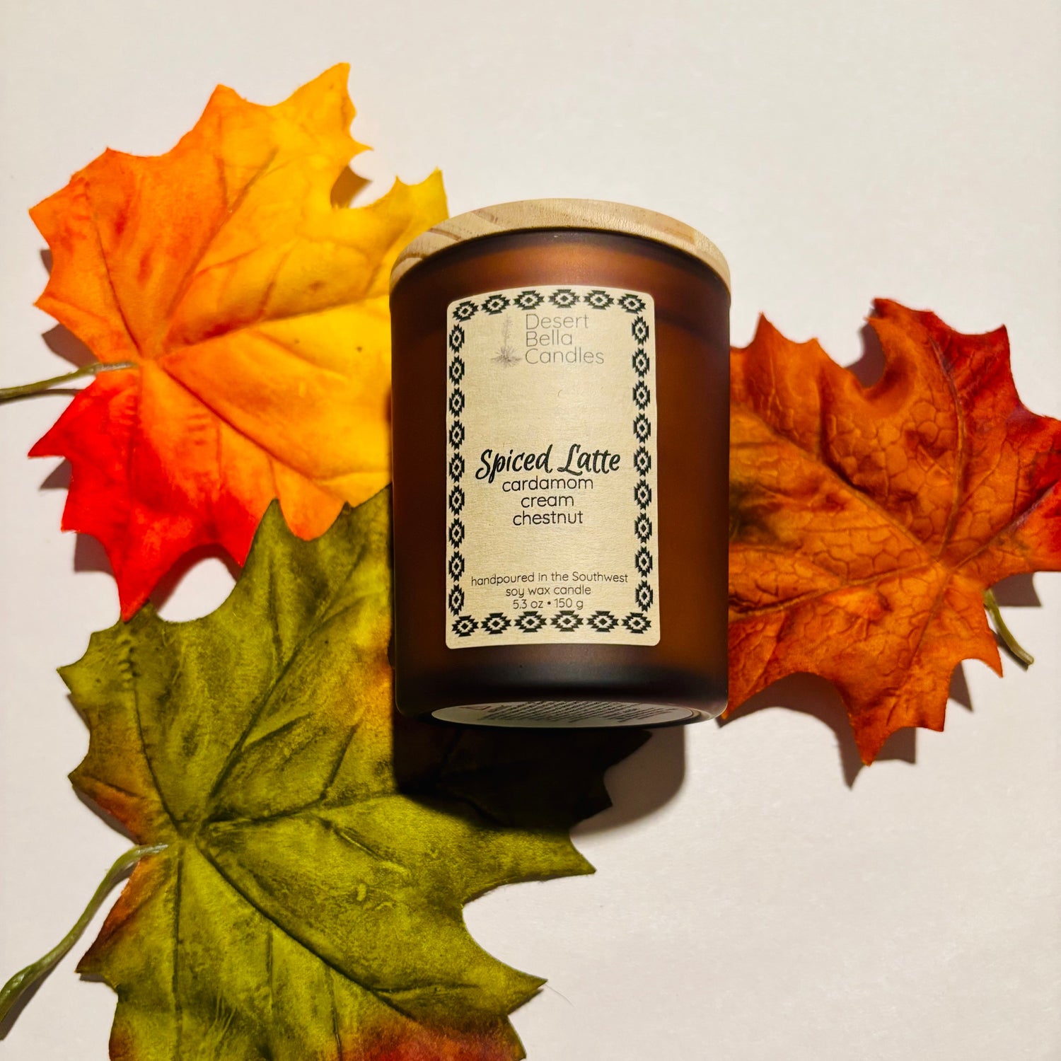 Spiced Latte candle with autumn leaves on a light background